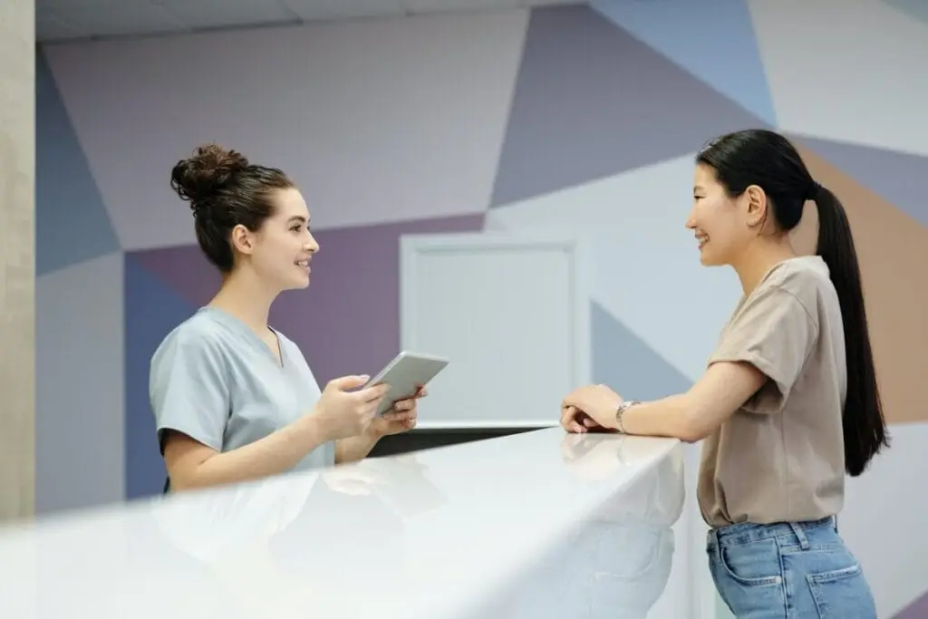two women at a desk - front desk medical receptionist concept